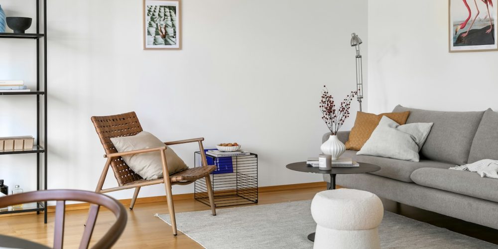 a lounge room with a grey sofa and accent chair in brown leather this is an example of an investment property in Sydney