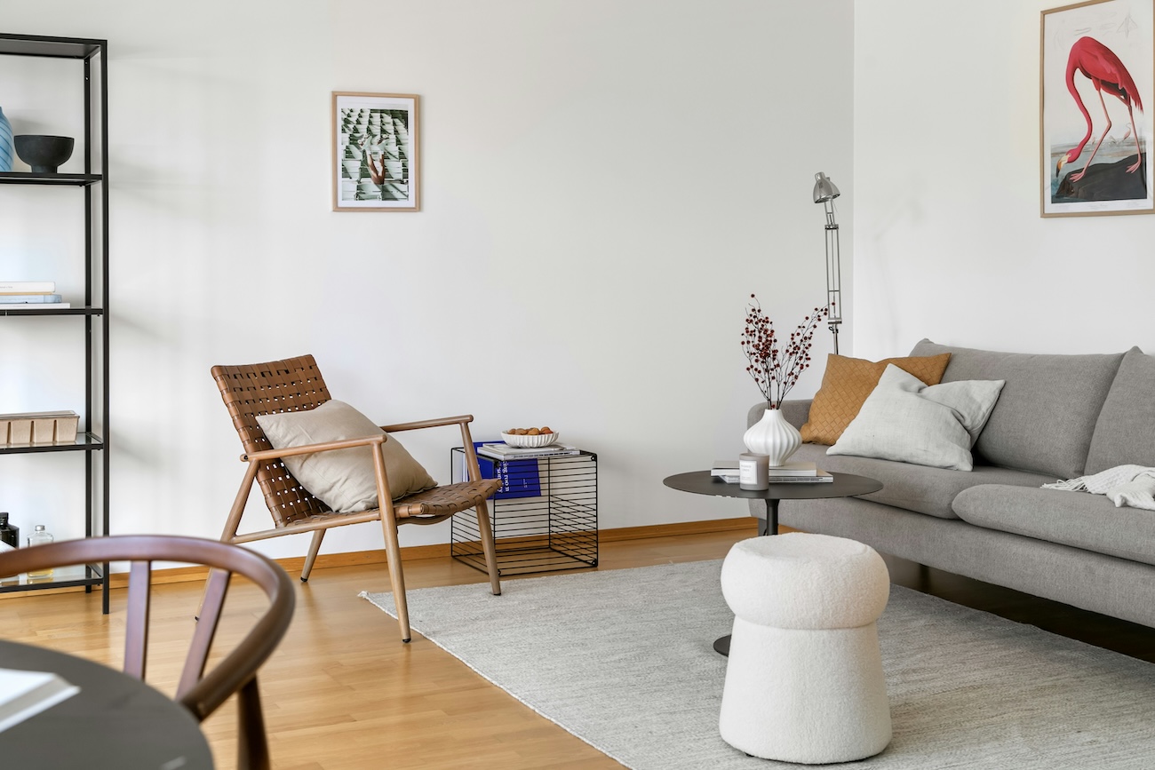 a lounge room with a grey sofa and accent chair in brown leather this is an example of an investment property in Sydney