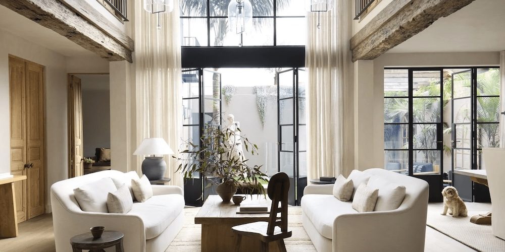 large soaring ceilings with drapes and white lounges with a small dog
