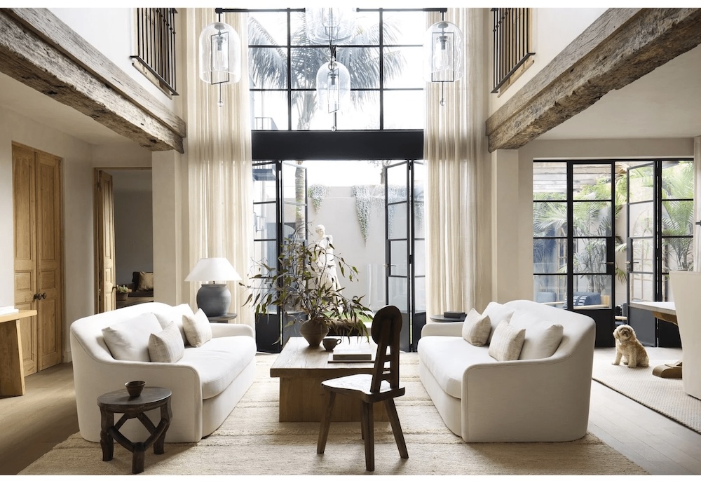 large soaring ceilings with drapes and white lounges with a small dog