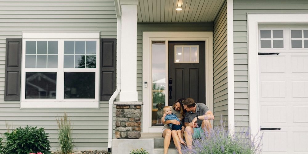 a family sitting on the steps outside their new family home
