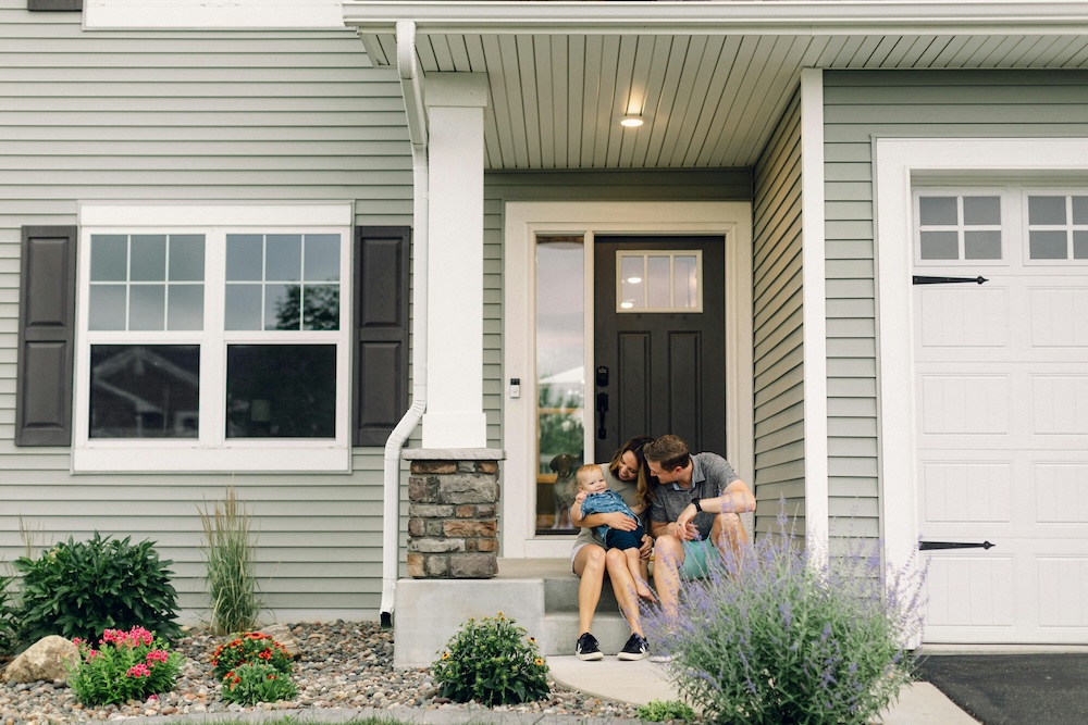a family sitting on the steps outside their new family home